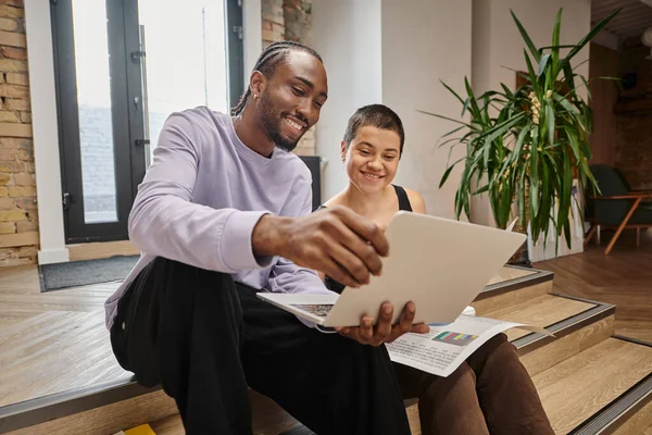 Homme afro-américain heureux montrant le projet sur ordinateur portable à la femme, planification de démarrage, idées, coworking — Photo de stock