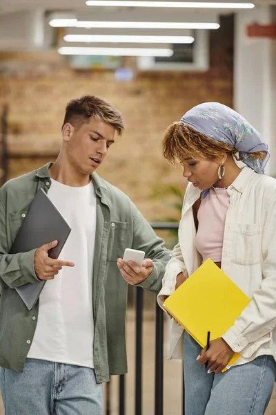 Young man showing smartphone to african american woman in coworking, planning startup, teamwork — Stock Photo