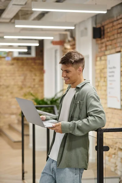 Homem alegre usando laptop, chamada de vídeo, coworking moderno, ambiente de escritório, geração z, inicialização — Fotografia de Stock