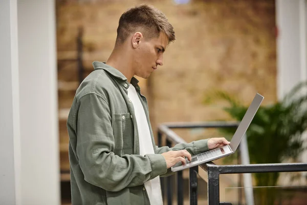 Vista lateral, homem usando laptop, coworking moderno, ambiente de escritório, geração z, ideias de inicialização — Fotografia de Stock