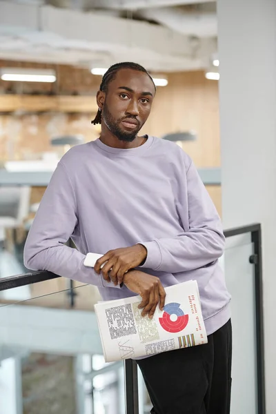 Afrikanisch-amerikanischer Mann hält Smartphone und Grafiken in der Hand, blickt auf Kamera, Generation Z, Start-up — Stockfoto