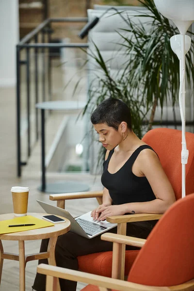 Jeune femme d'affaires utilisant ordinateur portable, coworking, culture de démarrage, gen z, smartphone, café à emporter — Photo de stock
