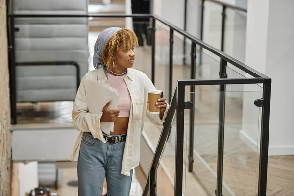 Mujer afro-americana positiva con frenillos sosteniendo papeles, proyecto de startup, coworking, escaleras - foto de stock