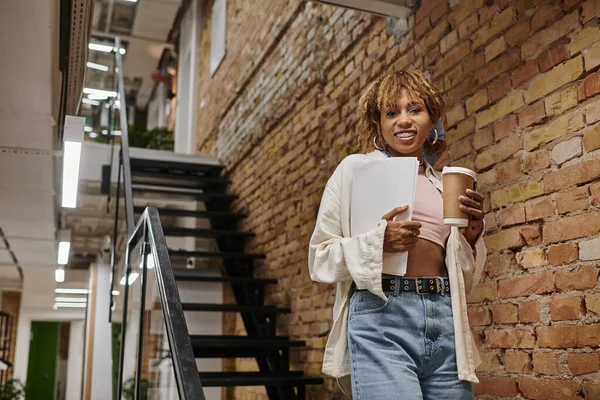 Happy african american manager with braces holding papers, startup project, standing in coworking — Stock Photo