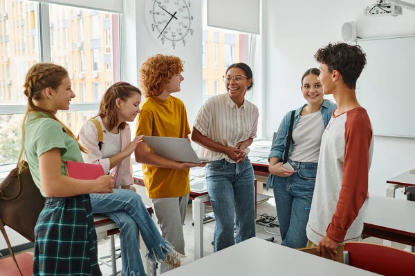 Teenage students smiling near african american teacher in classroom, black woman, back to school — Stock Photo