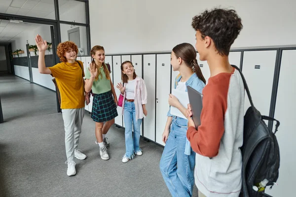 Back to school, happy teen students waving hands and looking at classmates during new school year — Stock Photo