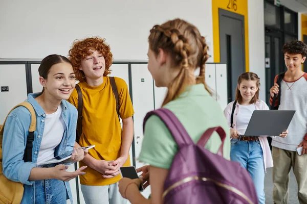 Вернуться в школу, подростки разговаривают в школьном коридоре, держат устройства и общаются друг с другом — стоковое фото
