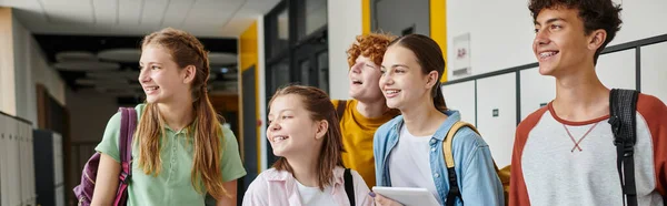 Banner, happy teenage schoolkids looking away and standing in school hallway, teen classmates — Stock Photo