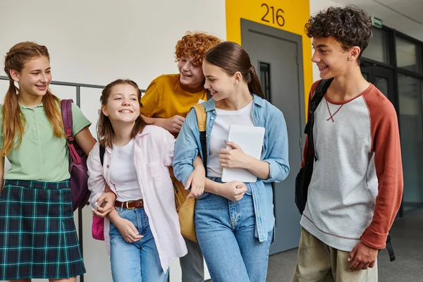 Назад в школу, веселые одноклассники улыбаются в школьном коридоре, студенческая жизнь, друзья веселятся — стоковое фото