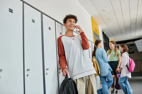 Heureux écolier avec bretelles ayant appel téléphonique, parler sur smartphone dans le couloir de l'école, flou — Photo de stock