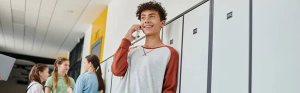 Bannière, écolier heureux avec bretelles ayant un appel téléphonique, parler sur smartphone dans le couloir de l'école, flou — Photo de stock
