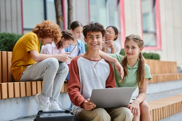 Повернутися до школи, щасливий хлопчик-підліток і дівчинка, що сидить поруч з ноутбуком, студентами і вчителем, різноманітність — стокове фото