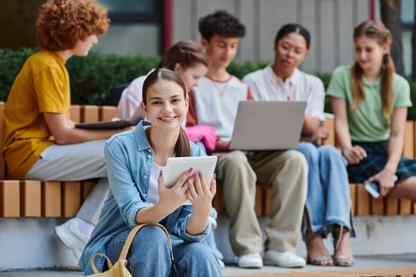 Volver a la escuela, chica feliz sosteniendo tableta digital, diversidad, desenfoque, profesor y estudiantes, e-learn - foto de stock