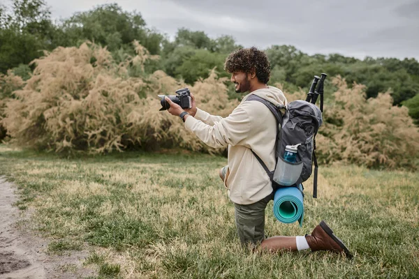 Веселий індійський фотограф з рюкзаком фотографує професійну камеру, природне місце розташування — стокове фото