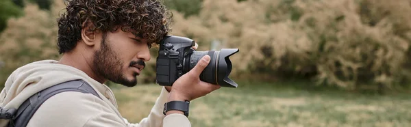 Fotógrafo indio enfocado tomando fotos en cámara profesional, turista, ubicación natural, pancarta - foto de stock