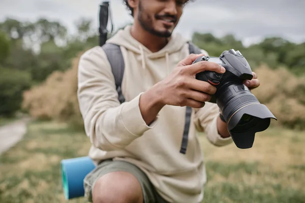 Cropped view of cheerful indian photographer using professional camera, natural location, travel — Stock Photo