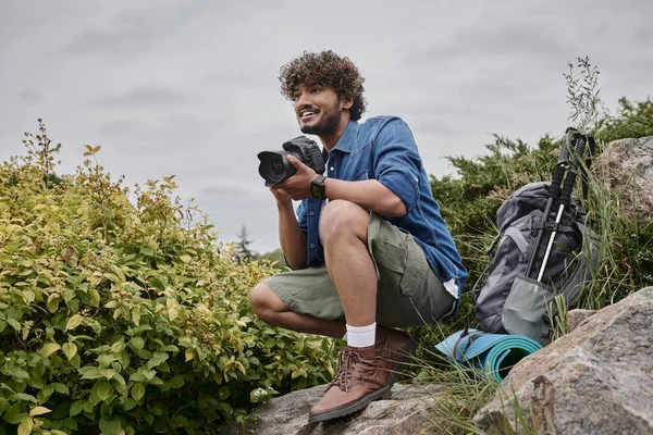 Concepto de fotógrafo de viajes, hombre indio feliz tomando fotos en la cámara en lugar natural, pancarta - foto de stock