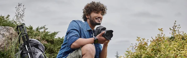 Concepto de fotógrafo de viajes, hombre indio feliz tomando fotos en cámara digital en lugar natural - foto de stock