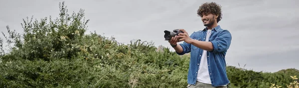Concepto de aventura y fotografía, vista recortada del hombre sosteniendo la cámara y caminando en lugar natural - foto de stock