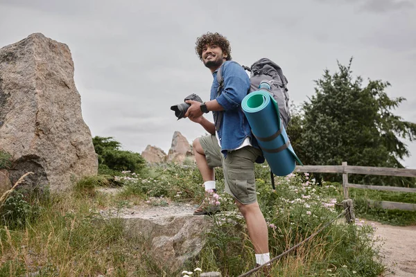 Concepto de viaje y fotografía, mochilero indio feliz utilizando la cámara digital durante el viaje por la naturaleza - foto de stock
