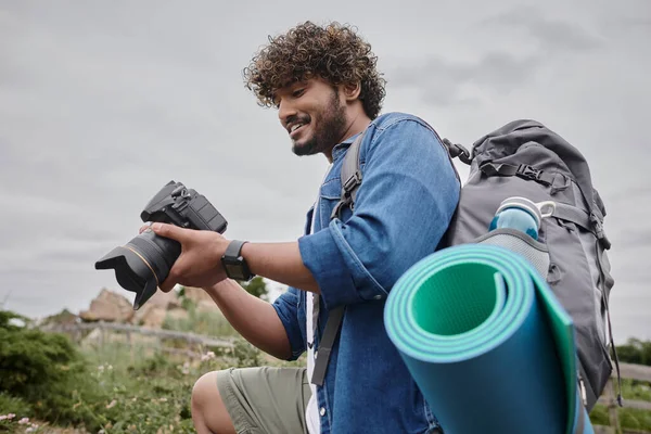 Travel photography concept, happy indian backpacker holding digital camera during journey — Stock Photo