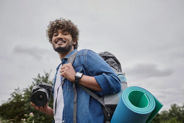 Fotografía de viaje y concepto de la naturaleza, mochilero indio feliz celebración de la cámara digital durante el viaje - foto de stock