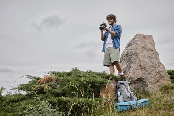 Фотография и концепция природы, индийский турист снимает на цифровую камеру и стоит на скале — стоковое фото