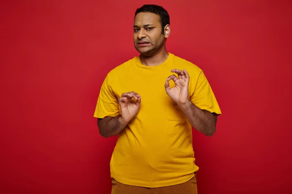 Emotional indian man in bright casual clothes making disgusted expression on red background — Stock Photo