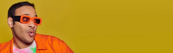Concetto di auto espressione, sorpreso uomo indiano in occhiali da sole arancioni su sfondo giallo, banner — Foto stock