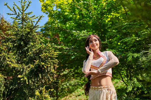 Carefree indian woman in stylish traditional attire dancing in summer park on sunny day — Stock Photo