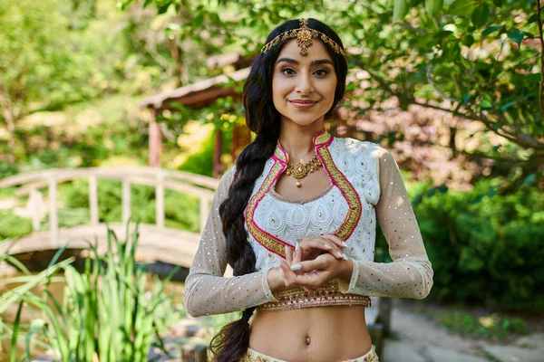Ritratto di attraente donna indiana in abbigliamento tradizionale sorridente alla macchina fotografica nel parco — Foto stock