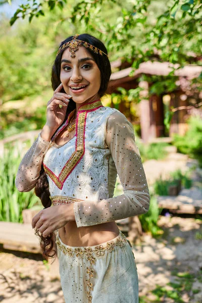 Alegre asiático mulher no vibrante tradicional roupas olhando para câmera no verão parque — Fotografia de Stock