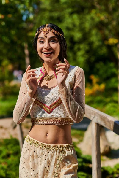 Здивована індійська жінка в традиційному одязі, дивлячись на камеру в сонячний день в літньому парку — стокове фото