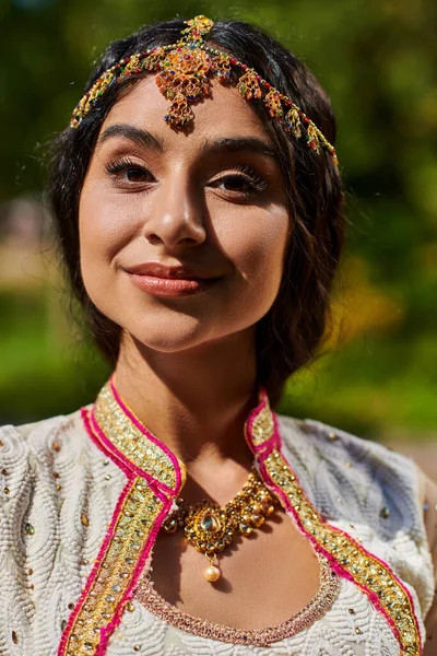 Portrait de jeune femme indienne brune en tenue authentique souriant à la caméra le jour de l'été dans le parc — Photo de stock