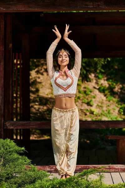 Style authentique, parc d'été, jeune femme indienne en tenue traditionnelle dansant les yeux fermés — Photo de stock