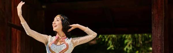 Взволнованная индийская женщина в яркой традиционной одежде танцы летом на открытом воздухе, баннер — стоковое фото