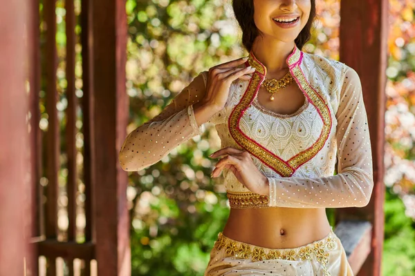 Vista recortada de la mujer india en traje elegante y tradicional sonriendo y bailando en el parque en verano - foto de stock
