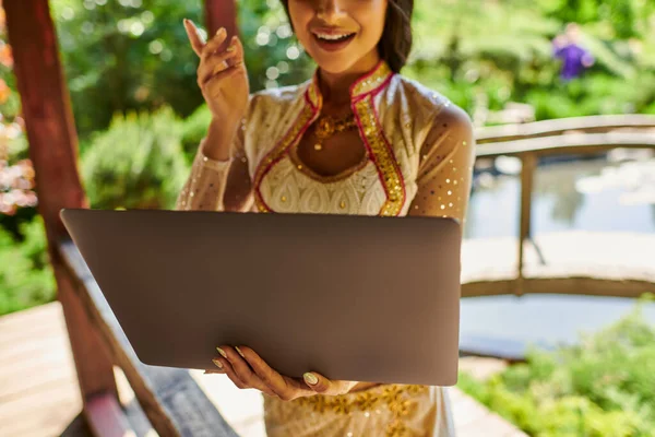 Cropped view of authentic style indian woman talking during video call on laptop on summer day — Stock Photo