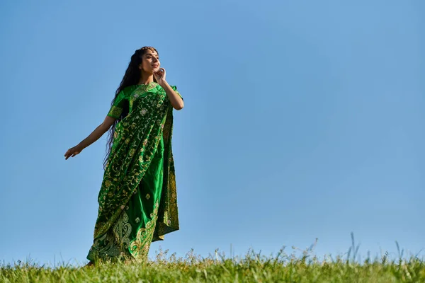 Лето и природа, молодая индийская женщина в традиционной одежде смотрит вдаль под голубым и ясным небом — стоковое фото