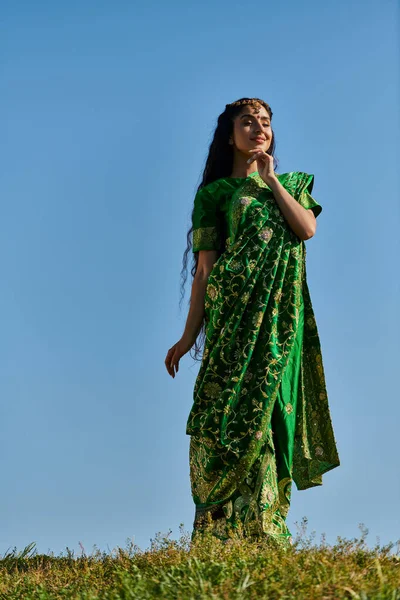 Young indian woman in elegant traditional sari in green field under blue sky, summer happiness — Stock Photo
