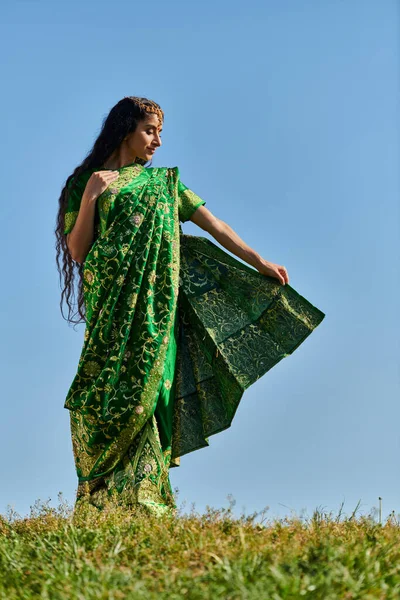 Культурное наследие, индийская женщина в традиционном сари на зеленом лугу под голубым летним небом — стоковое фото