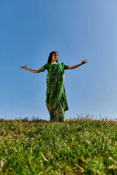 Традиційна мода, молода індійська жінка в сарі з простягнутими руками під блакитним літнім небом — стокове фото