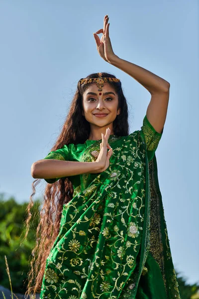 Ritratto di elegante giovane donna indiana in sari e matha patti in posa nel parco con cielo blu — Foto stock