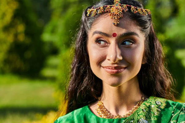 Portrait of pretty and smiling indian woman with bindi and matha patty standing outdoors — Stock Photo