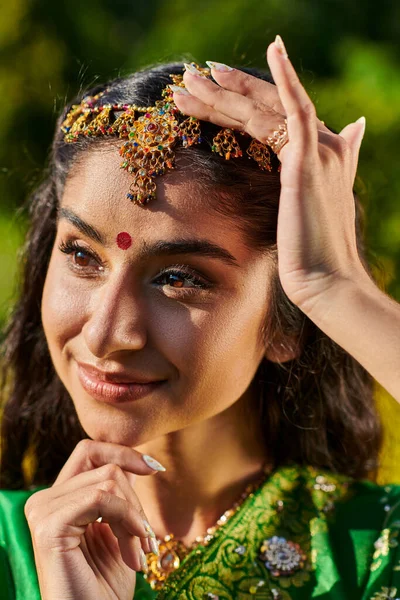 Retrato de mujer india elegante y alegre con bindi y matha patti de pie al aire libre - foto de stock