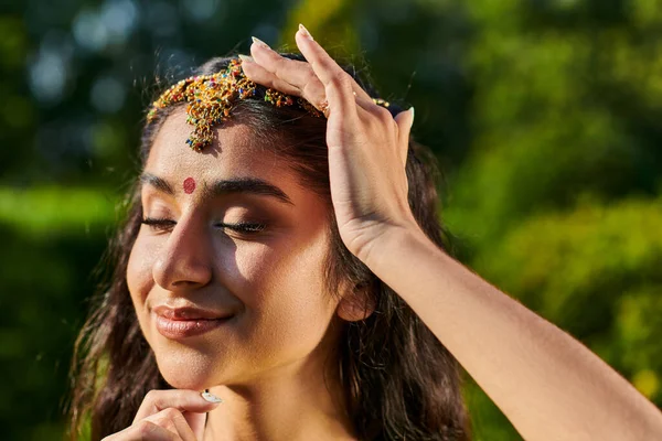 Portrait of pleased young indian woman with bindi and matha patty posing outdoors — Stock Photo