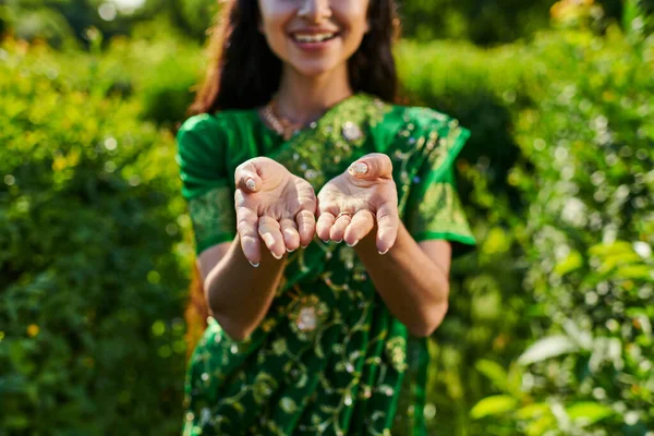 Corte vista de elegante jovem mulher no sari mostrando as mãos na câmera no parque borrado — Fotografia de Stock