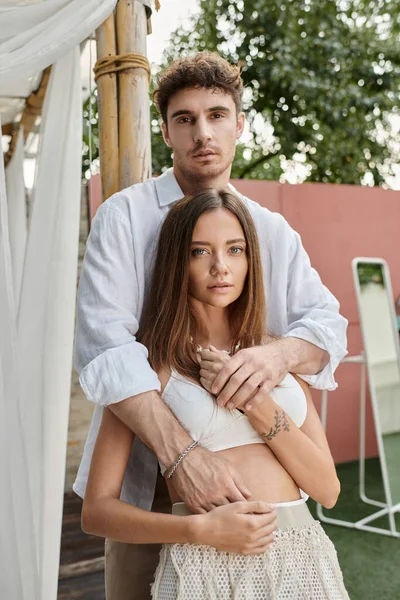 Hombre guapo y hermosa mujer en traje de verano blanco mirando a la cámara juntos, pareja vinculación - foto de stock