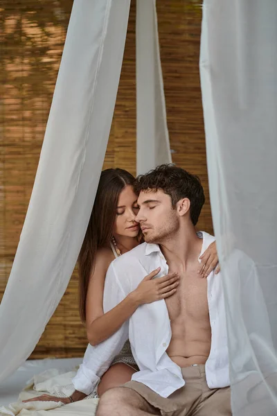Романтическая пара, красивая женщина обнимает мужчину в белой одежде и сидит в частном павильоне — стоковое фото