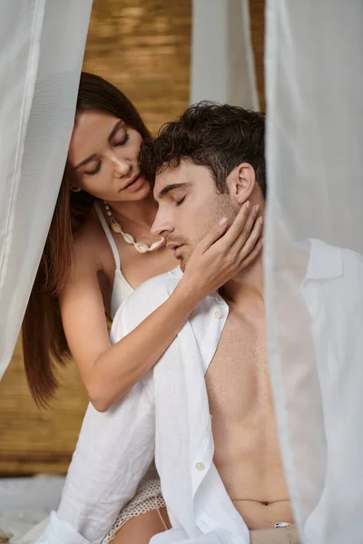 Romantic couple, beautiful woman touching cheek of man and sitting in private pavilion, seduction — Stock Photo
